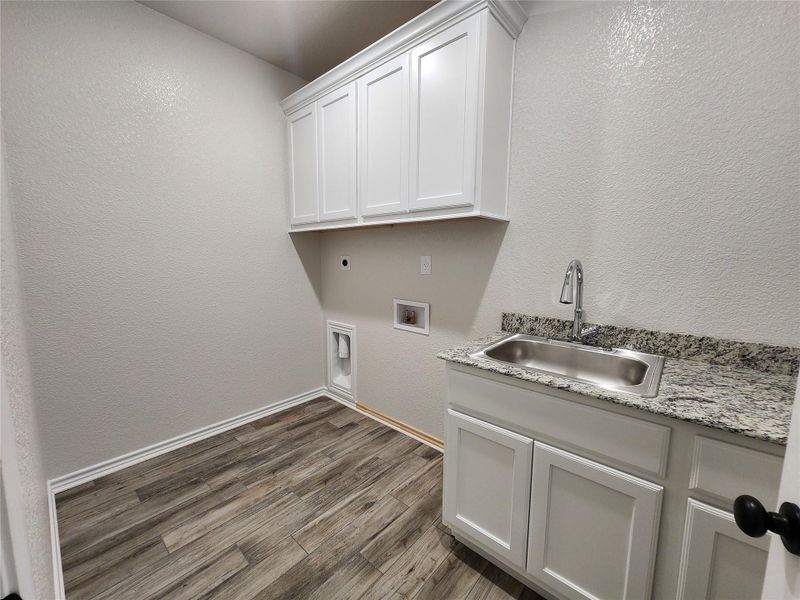 Washroom featuring a textured wall, cabinet space, dark wood-style flooring, washer hookup, and electric dryer hookup