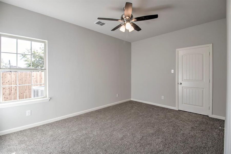 Empty room featuring ceiling fan and dark carpet