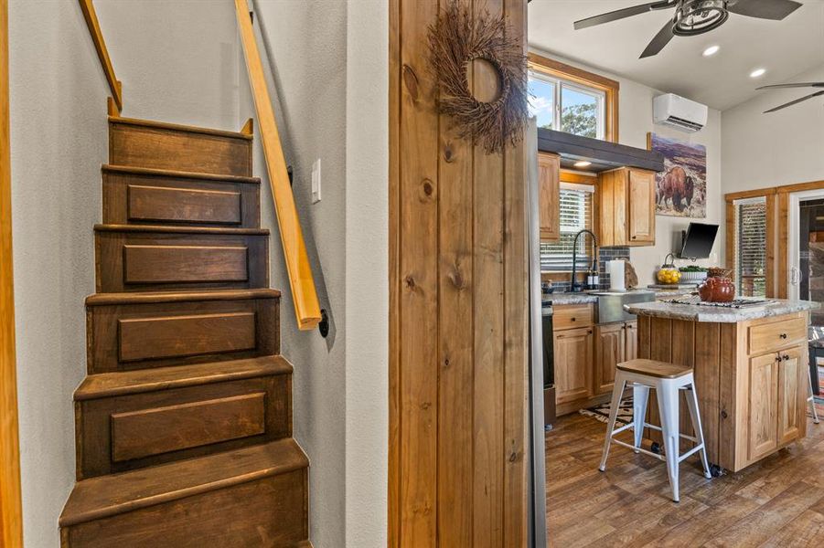 Kitchen featuring ceiling fan, dark wood-style flooring, recessed lighting, a center island, and a kitchen bar