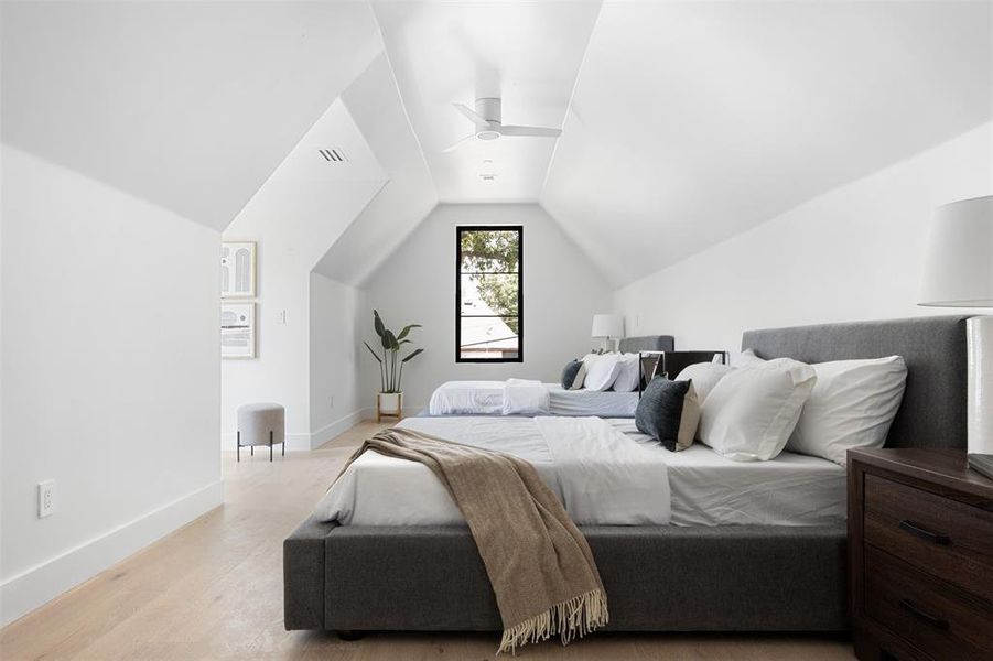 Bedroom with light hardwood / wood-style floors, vaulted ceiling, and ceiling fan