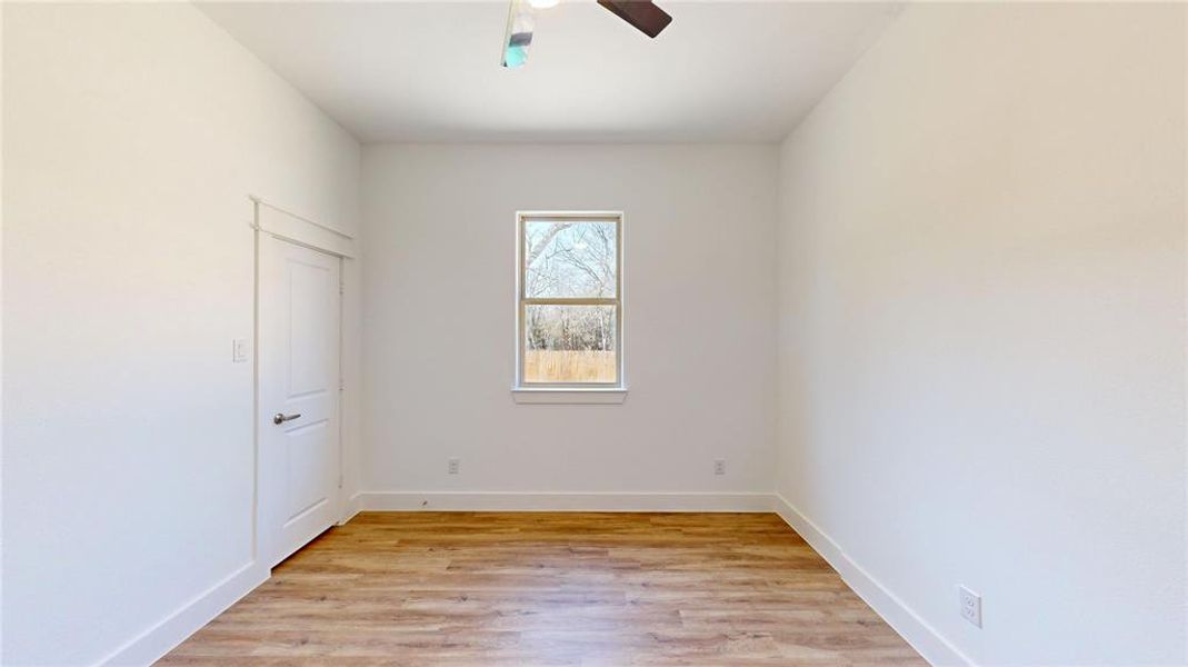 Spare room with light wood-type flooring, ceiling fan, and baseboards