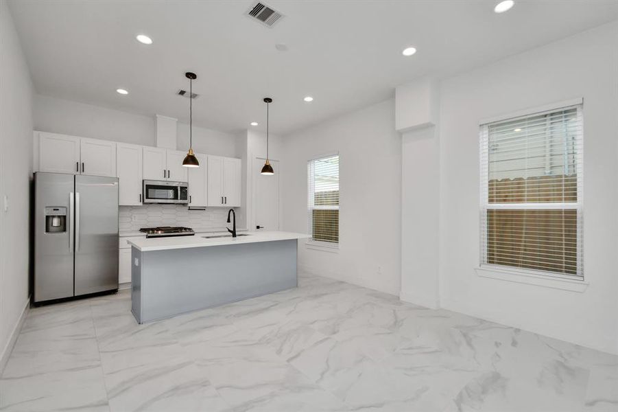 Discover culinary delights in this modern kitchen equipped with warm and elegant light fixtures, stainless steel appliances that elevate your cooking experience.