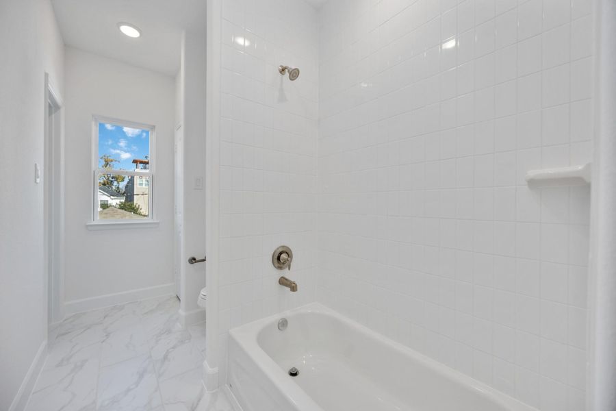 Flooded with light and finished with care, this hall bath delivers both function and finesse. Bonus points for that deep tub and elevated tilework.
