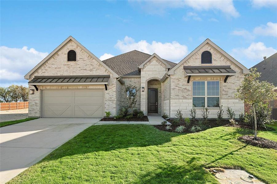 View of front facade featuring a garage and a front lawn