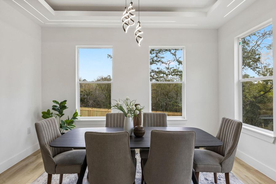 An elegant tray ceiling with custom lighting highlights this serene dining space.