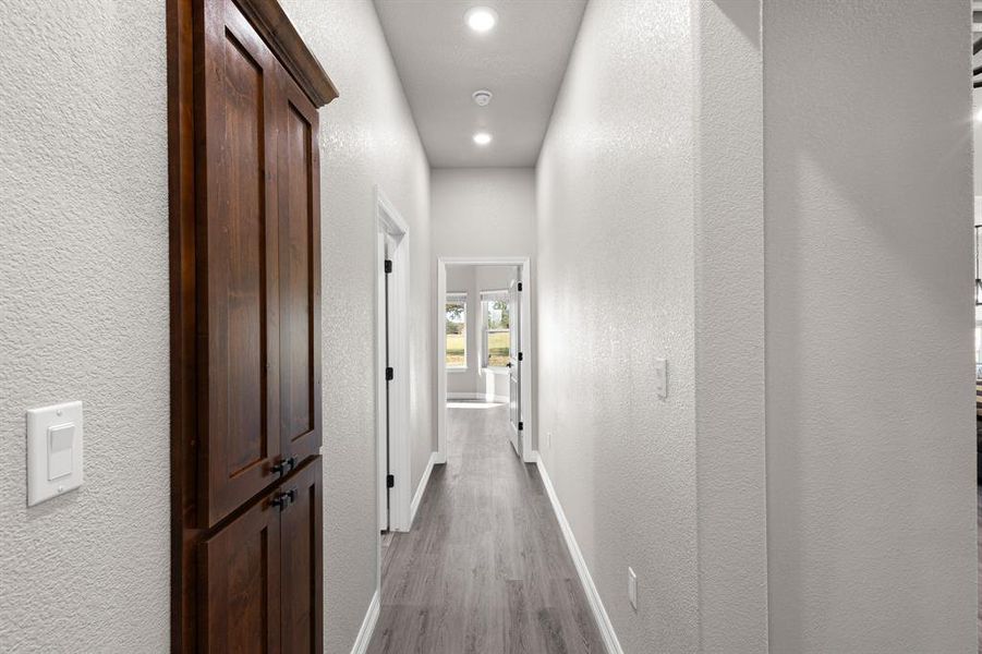 Corridor featuring a textured wall, recessed lighting, and light wood-style floors