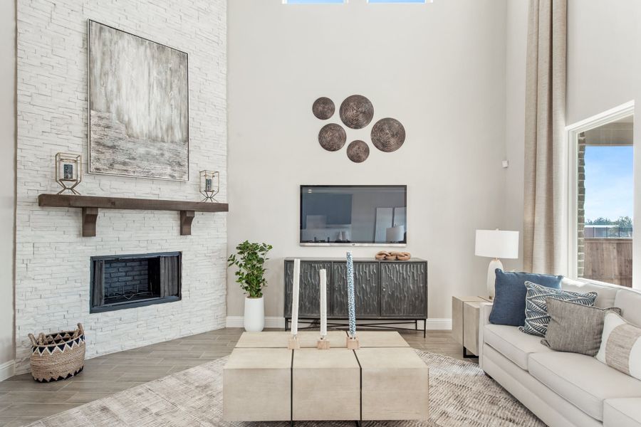 Living room with two-story ceiling, white stone fireplace, neutral sofa, and wall-mounted TV Living room with two-story ceiling, white stone fireplace, neutral sofa, and wall-mounted TV