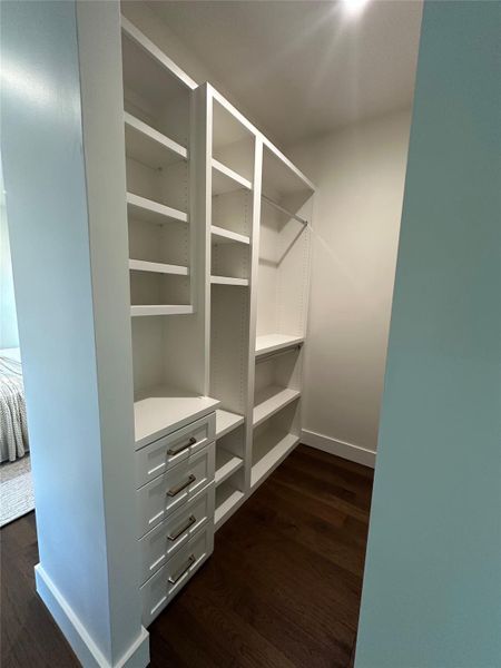 Custom walk-in closet featuring built-in shelving, integrated drawer storage with brushed nickel hardware, and wood-finish flooring