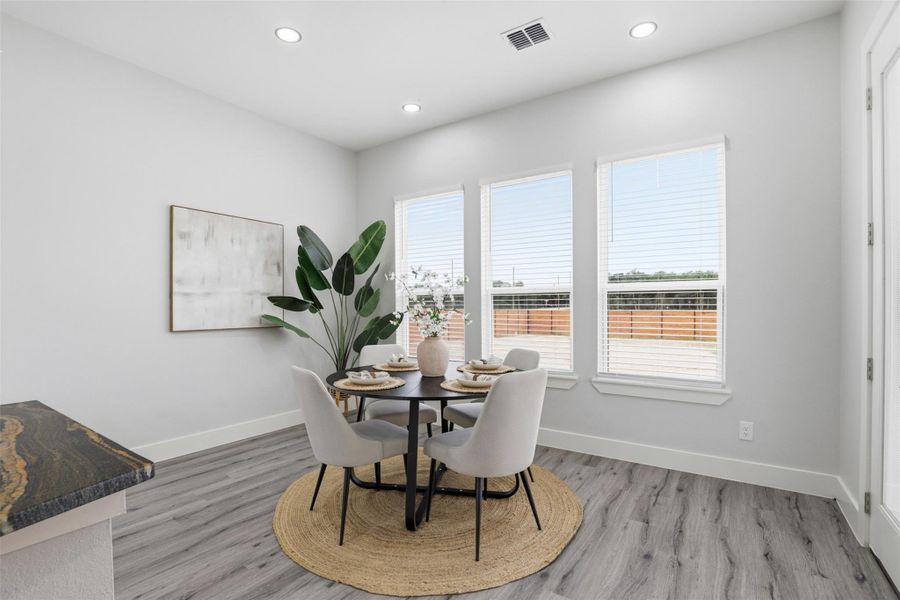Dining area with wood-finish flooring, recessed lighting, and a countertop featuring natural stone