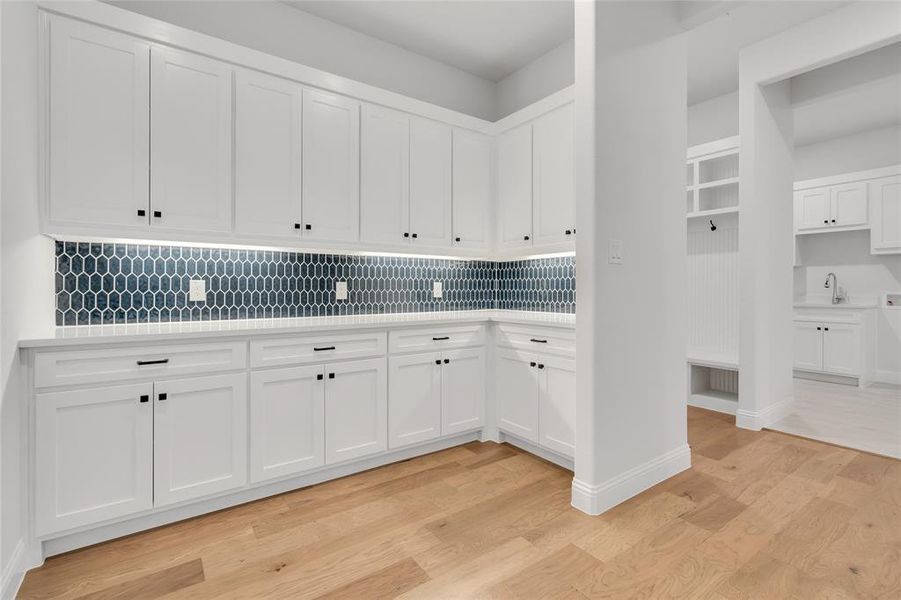 Kitchen with sink, white cabinetry, tasteful backsplash, and light hardwood / wood-style flooring