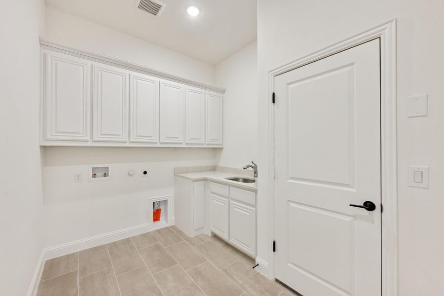Laundry room with white upper cabinets, utility sink, washer and dryer hookups, and tile floors Laundry room with white upper cabinets, utility sink, washer and dryer hookups, and tile floors