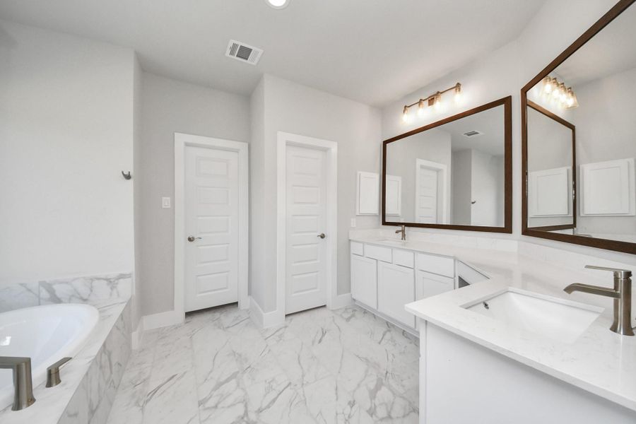 Escape to a spa-like oasis in this primary bathroom. Enjoy a walk-in shower with tile surround, a separate garden tub with custom detailing, and an elegant vanity featuring light countertops, modern hardware, and beautiful recessed and vanity lights. Experience luxury and relaxation in every detail. Escape to a spa-like oasis in this primary bathroom. Enjoy a walk-in shower with tile surround, a separate garden tub with custom detailing, and an elegant vanity featuring light countertops, modern hardware, and beautiful recessed and vanity lights. Experience luxury and relaxation in every detail.