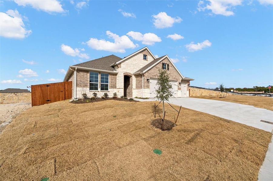 View of front of home with brick siding, driveway, a garage, a gate, and stone siding