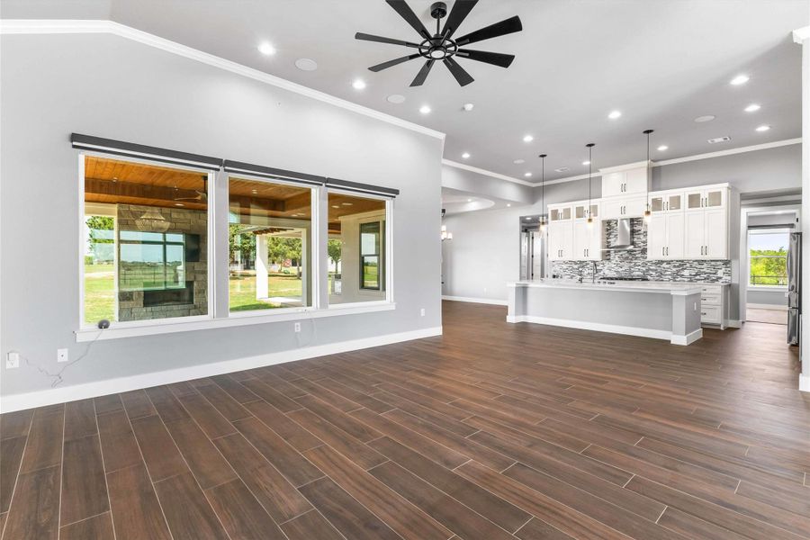 Unfurnished living room with ornamental molding, ceiling fan, recessed lighting, and dark wood finished floors Unfurnished living room with ornamental molding, ceiling fan, recessed lighting, and dark wood finished floors