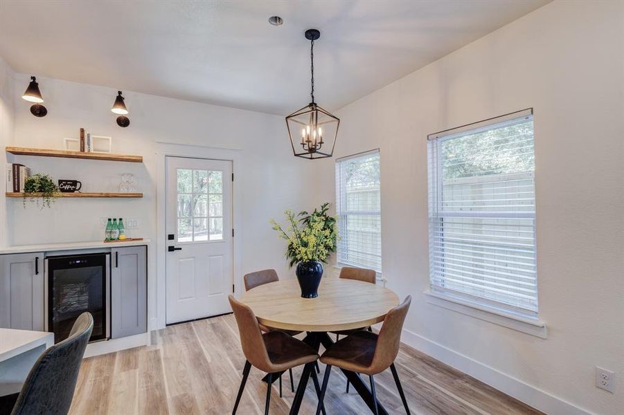 Dining area featuring beverage cooler, light hardwood / wood-style flooring, plenty of natural light, and a notable chandelier