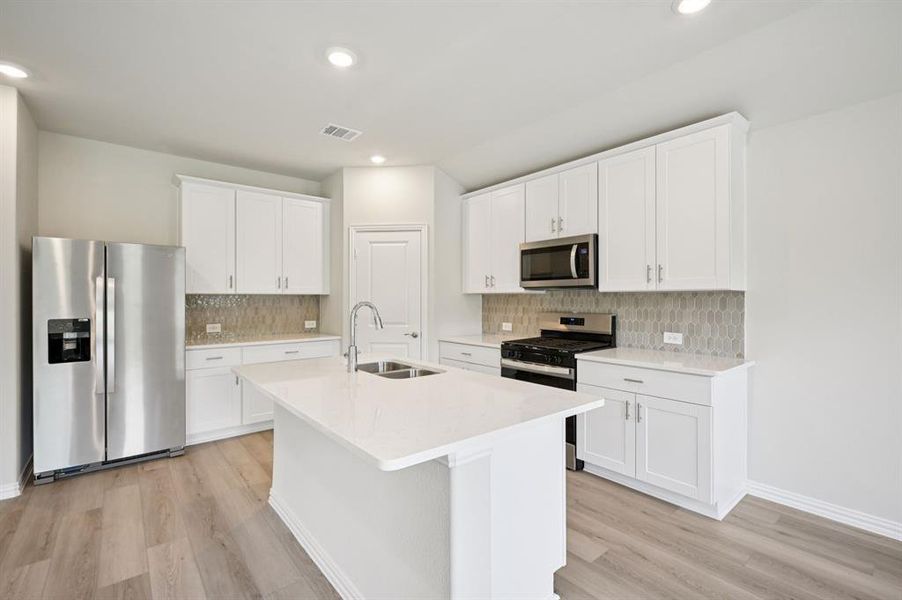 Kitchen with stainless steel appliances, white cabinetry, light wood-style flooring, a center island with sink, recessed lighting, and a gas range.
