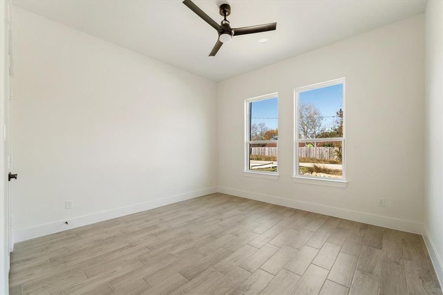 Secondary bedroom with forward facing windows, a ceiling fan, 2 recessed lights, and a closet. No carpet throughout the whole house!