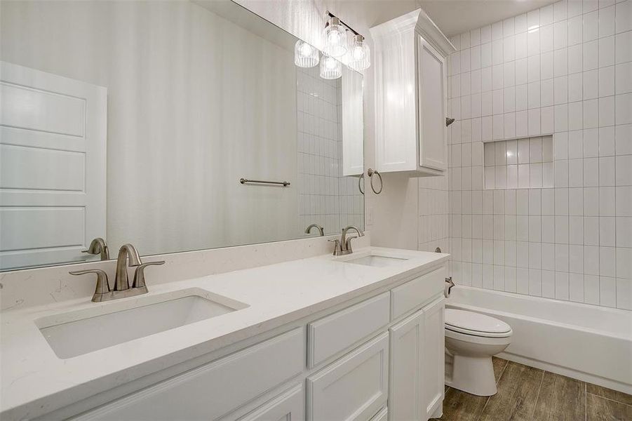 Full bathroom with vanity, toilet, hardwood / wood-style flooring, and tiled shower / bath