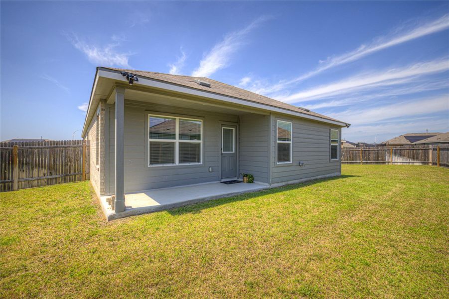 A well-maintained yard embraces a cozy home with a covered patio, ideal for outdoor relaxation.