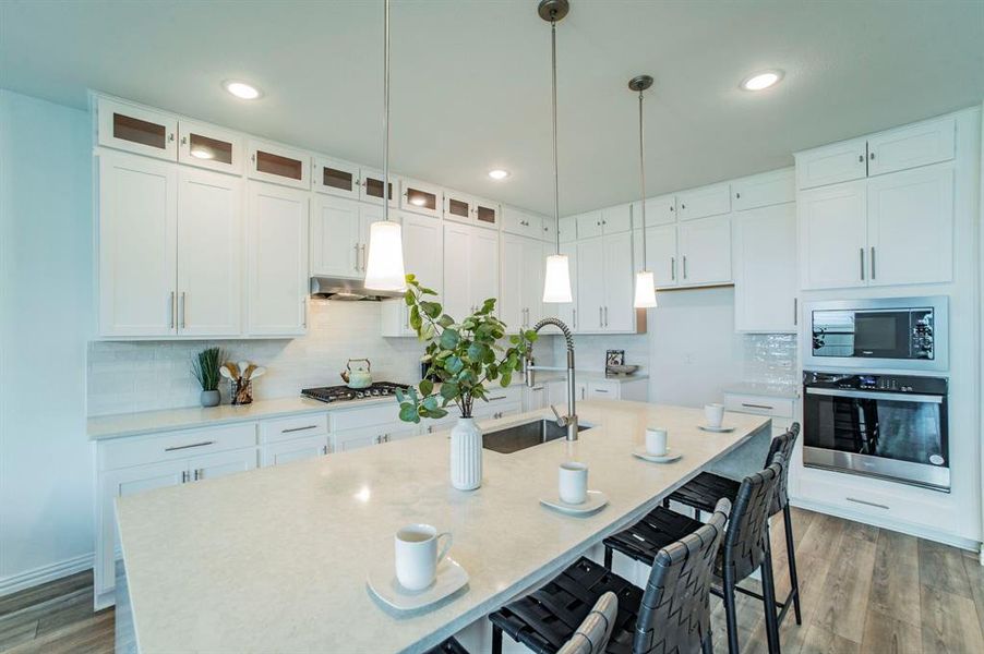 Kitchen featuring a kitchen bar, stainless steel appliances, white cabinetry, decorative light fixtures, and recessed lighting Kitchen featuring a kitchen bar, stainless steel appliances, white cabinetry, decorative light fixtures, and recessed lighting