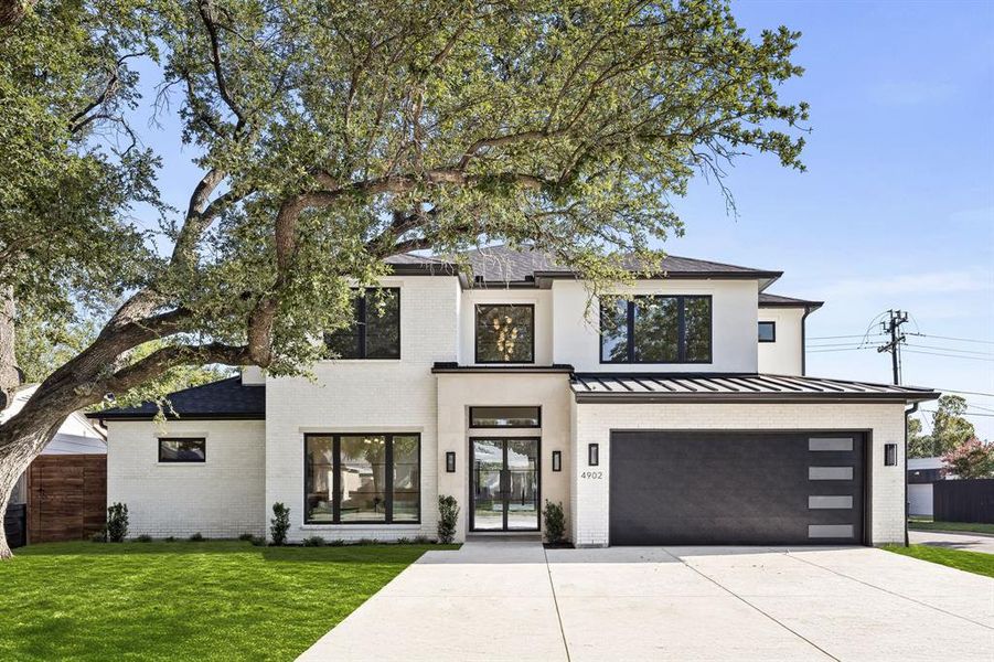 Contemporary home with brick siding, a front lawn, an attached garage, and concrete driveway Contemporary home with brick siding, a front lawn, an attached garage, and concrete driveway