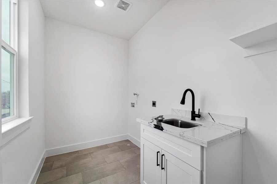 The laundry room upstairs offers a custom cabinet as well as a sink for additional functionality.