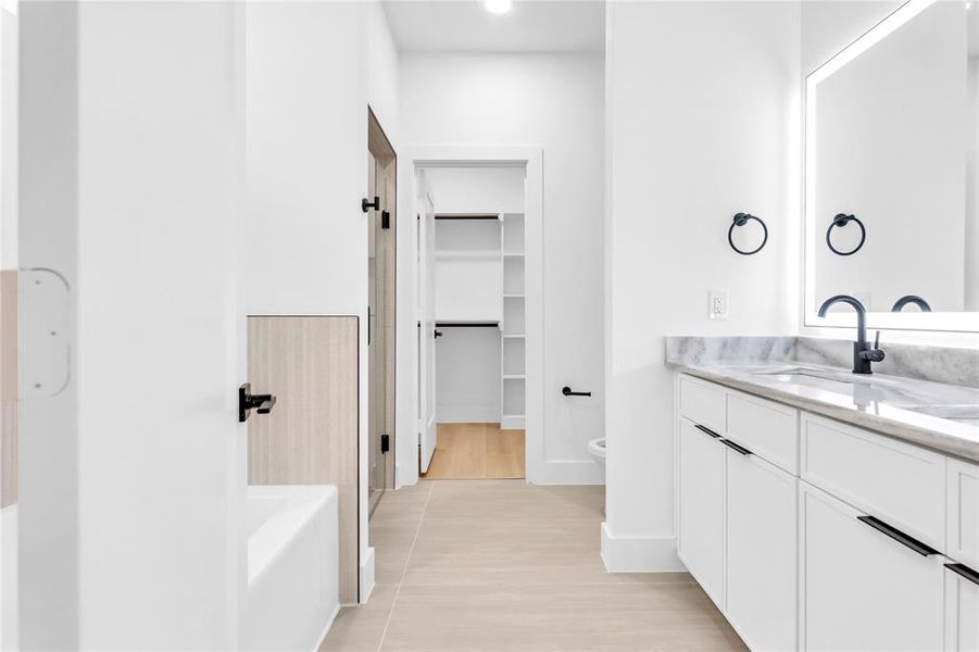Full bath with vanity, a walk in closet, and a bathtub
