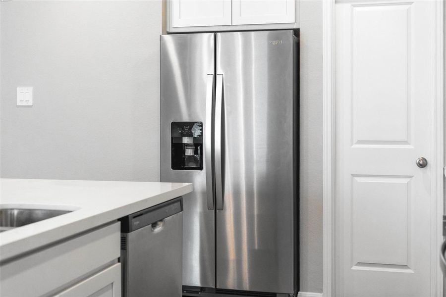 Kitchen comes equipped with a side-by-side Whirlpool refrigerator.