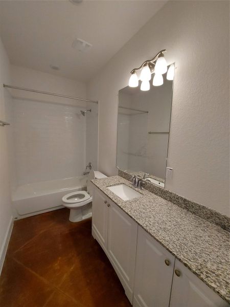 Full bathroom with vanity, bathing tub / shower combination, and dark tile patterned floors
