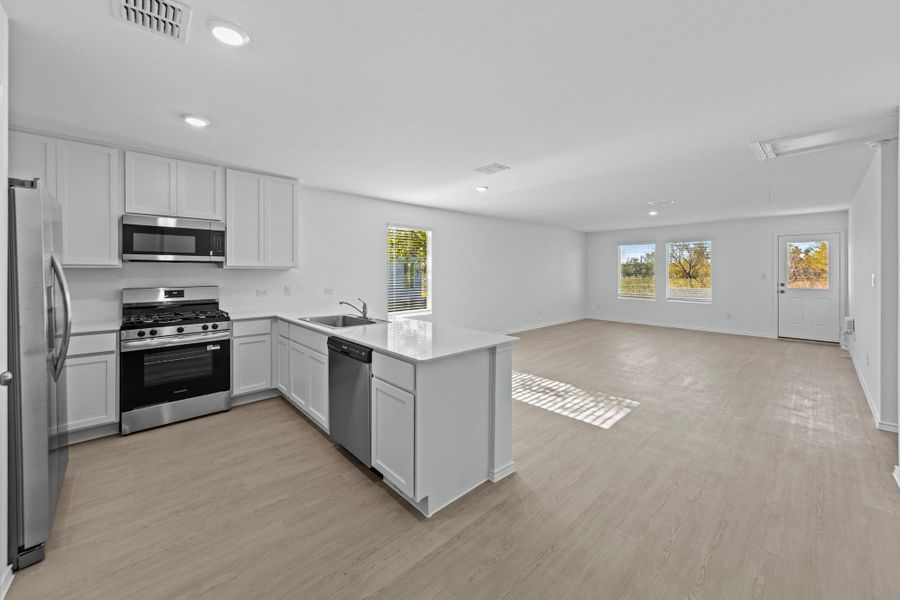 Kitchen featuring a peninsula, stainless steel appliances, plenty of natural light, white cabinets, and recessed lighting Kitchen featuring a peninsula, stainless steel appliances, plenty of natural light, white cabinets, and recessed lighting