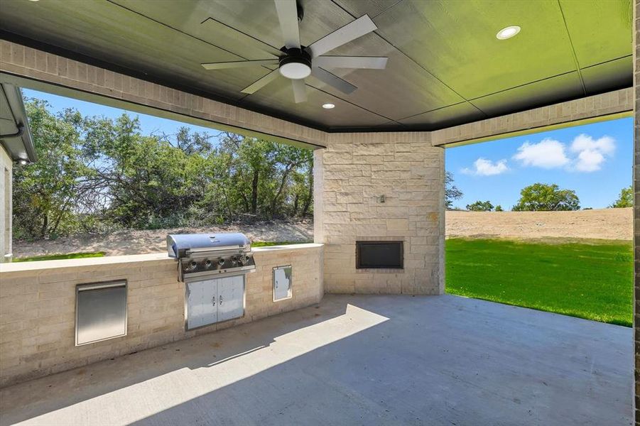 View of patio / terrace featuring ceiling fan, area for grilling, and an outdoor stone fireplace