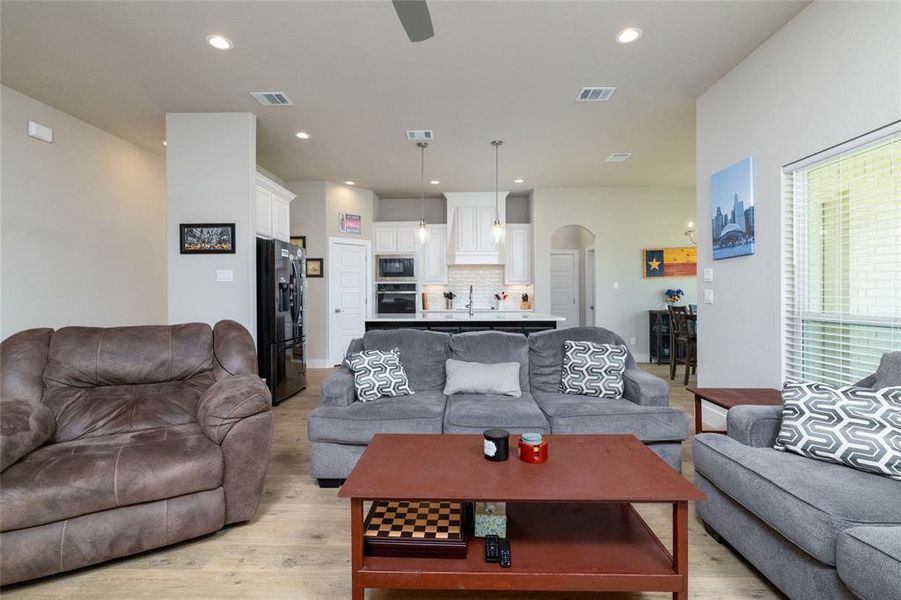 Living area featuring arched walkways, light wood-style flooring, recessed lighting, and ceiling fan