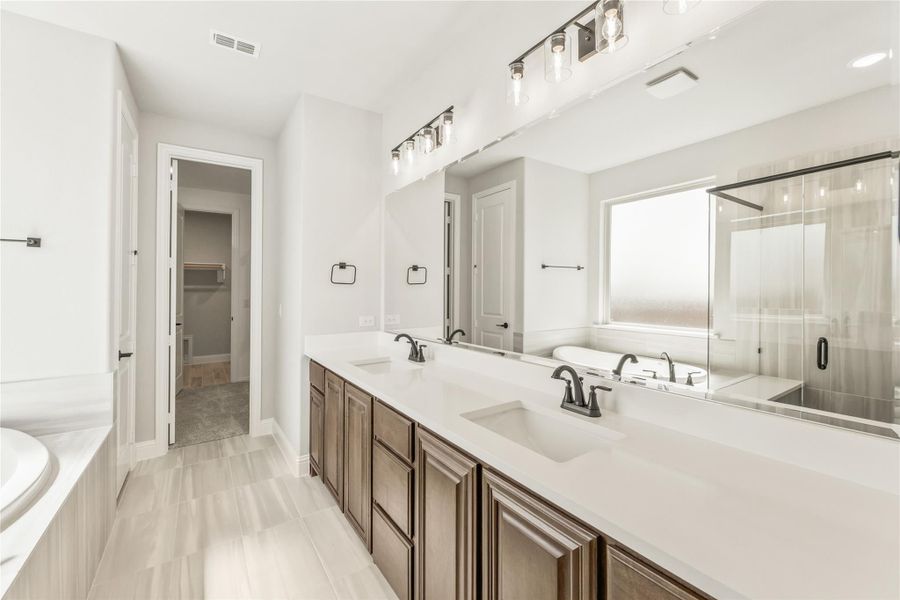 Master bathroom with double vanity, white countertops, soaking tub, and glass shower enclosure Master bathroom with double vanity, white countertops, soaking tub, and glass shower enclosure