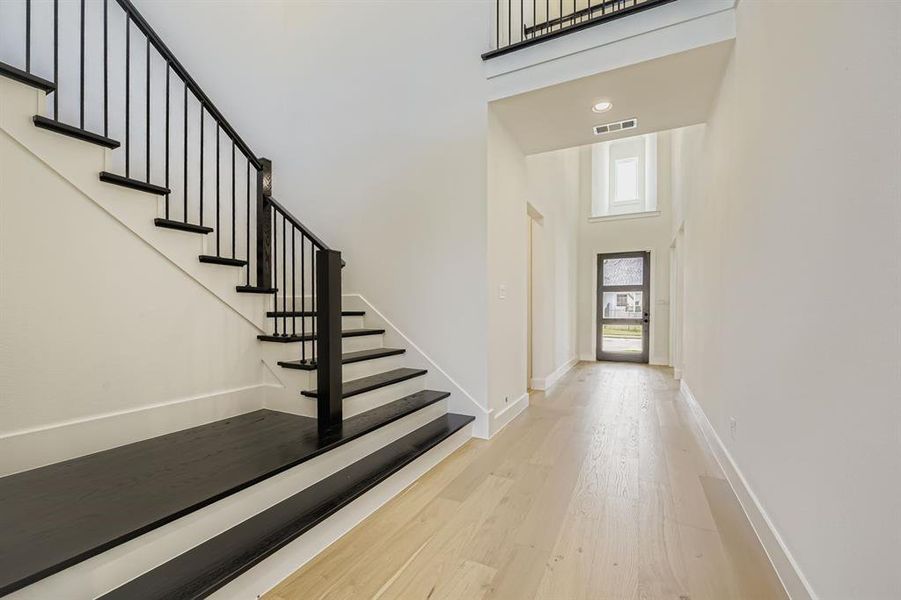 Foyer entrance featuring light wood-style flooring, stairway, recessed lighting, and a towering ceiling Foyer entrance featuring light wood-style flooring, stairway, recessed lighting, and a towering ceiling