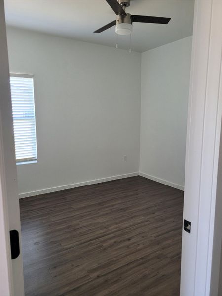 A well-lit bedroom features durable laminate flooring and a functional ceiling fan for optimal comfort.