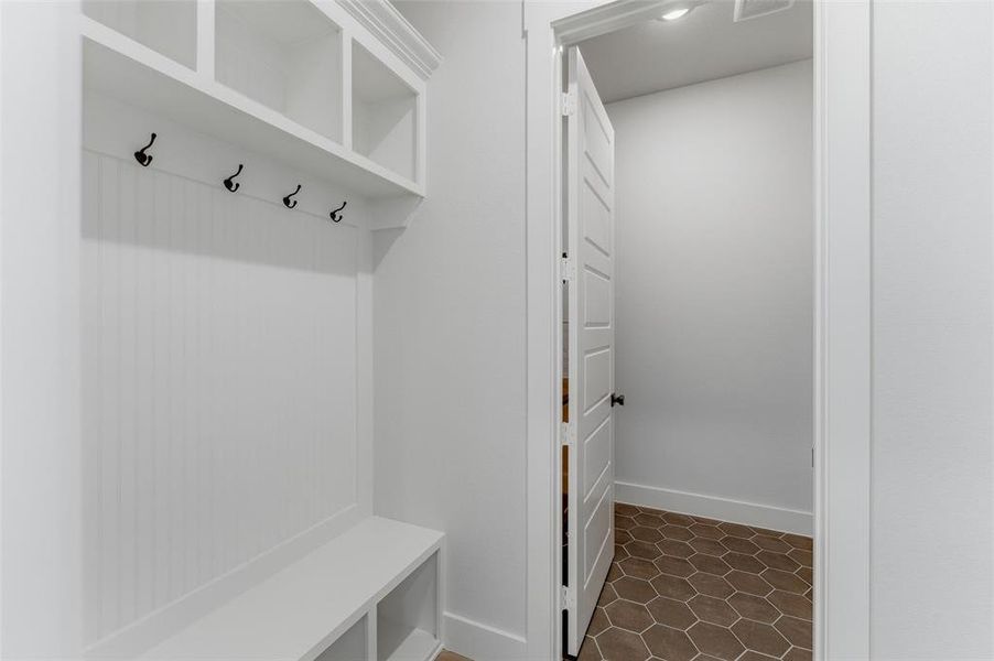 Mudroom featuring baseboards and dark tile patterned floors