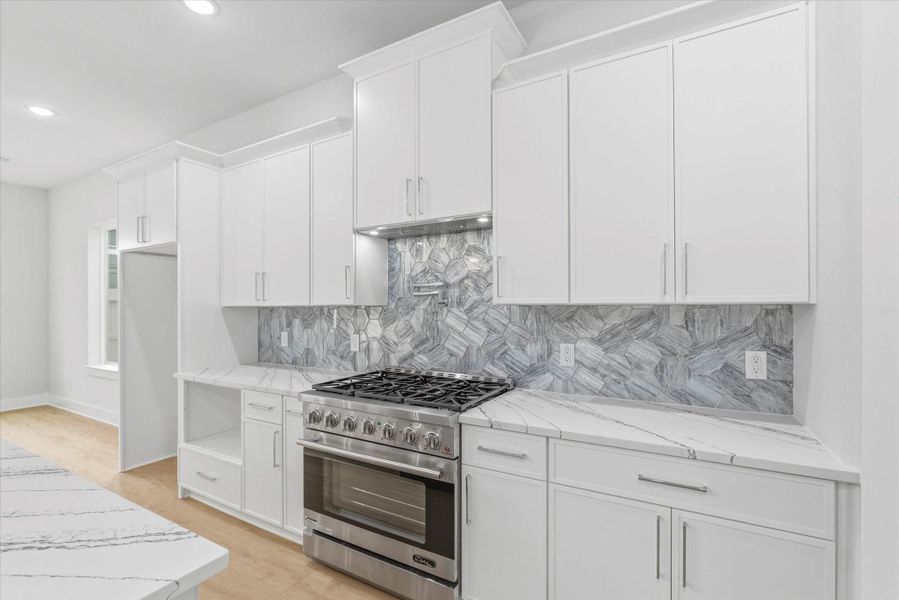The kitchen combines quarts countertops with a trendy hexagonal tile backsplash for a modern look. A convenient chrome pot filler, soft close cabinets, and a 36 inch Duro gas stove makes the space as functional as it is stylish.