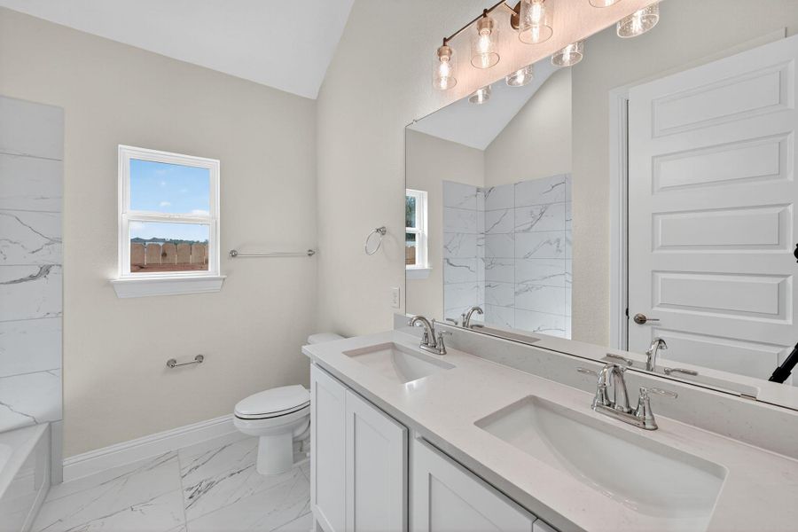 Bathroom with double vanity, light marble finish floors, plenty of natural light, lofted ceiling, and tub / shower combination Bathroom with double vanity, light marble finish floors, plenty of natural light, lofted ceiling, and tub / shower combination