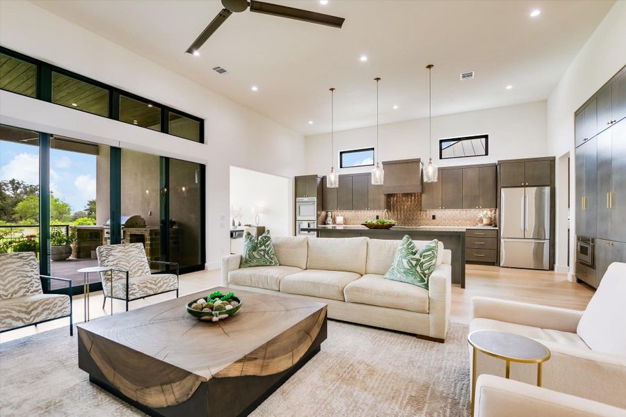 An open-concept living space with high ceilings and sliding glass doors seamlessly connects to an outdoor kitchen and patio.