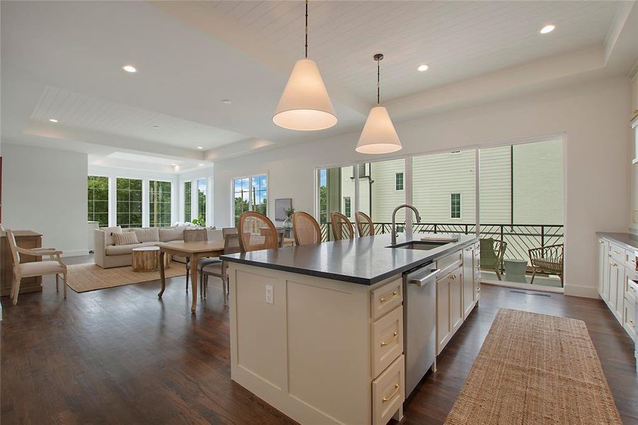 Kitchen featuring a center island with sink, dark hardwood flooring, a tray ceiling