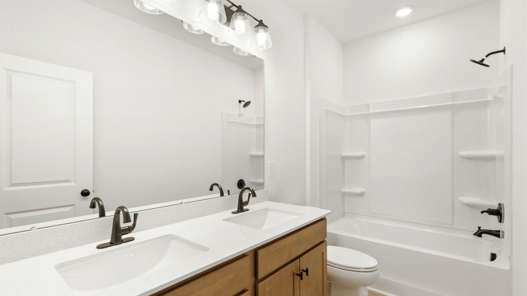 Stylish secondary bath with dual sinks at Chestnut Farms by DRB Homes