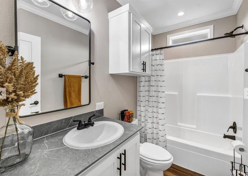 Full bathroom with vanity, shower / bath combo with shower curtain, crown molding, and dark wood-style floors