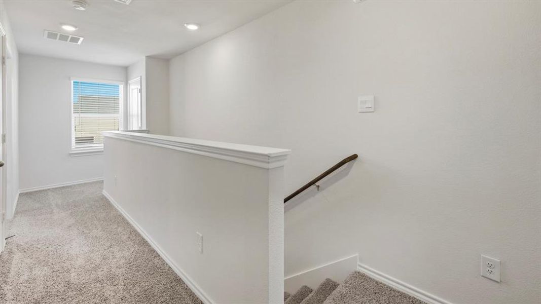 Hallway featuring light carpet and an upstairs landing