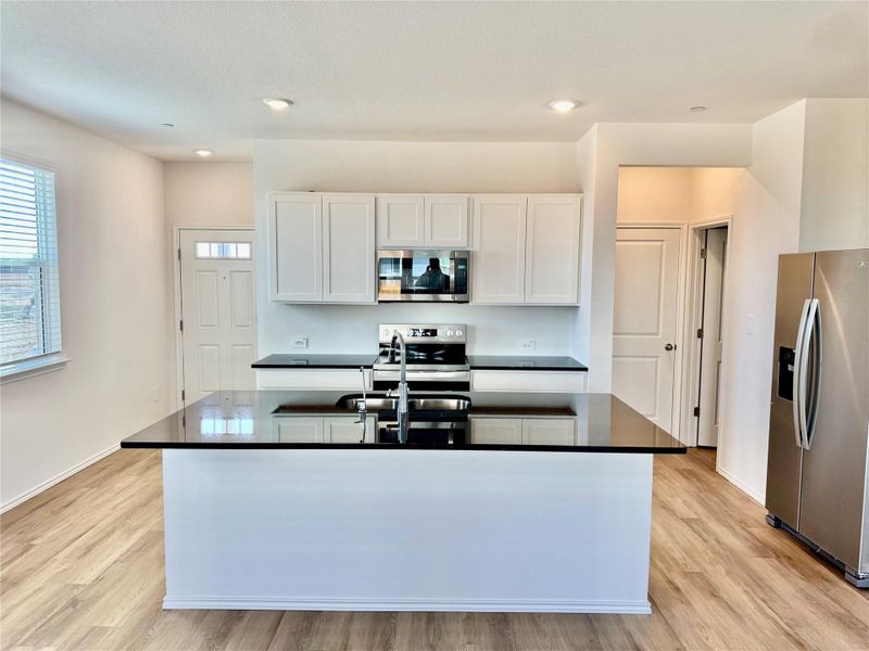 Kitchen with white cabinets, appliances with stainless steel finishes, light wood-style floors, a center island with sink, and recessed lighting