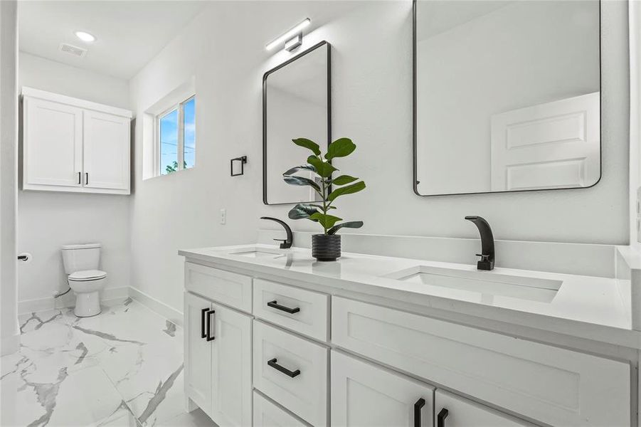 Full bath featuring marble finish flooring, double vanity, and recessed lighting