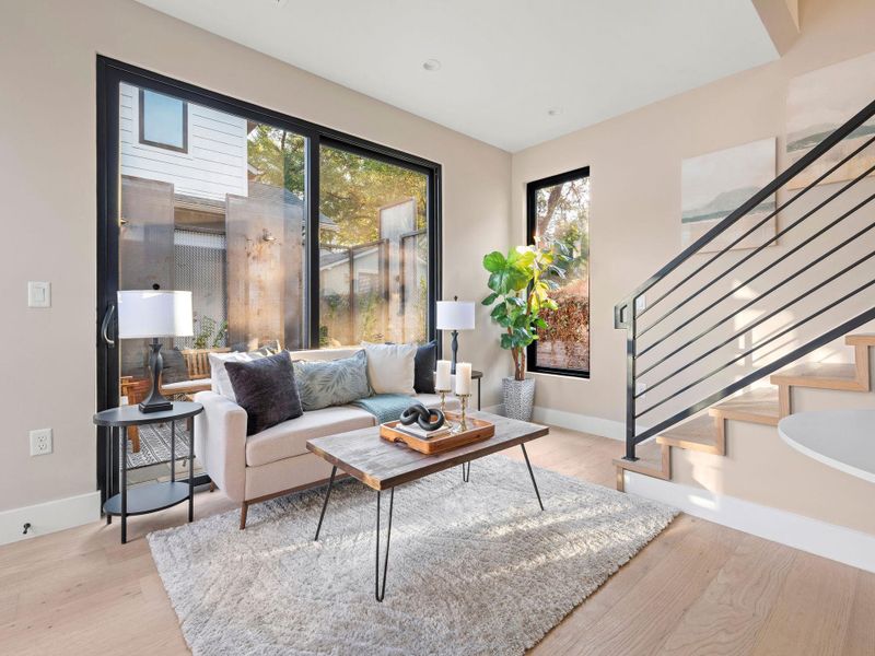 Living room with plenty of natural light, light wood-style floors, and stairs