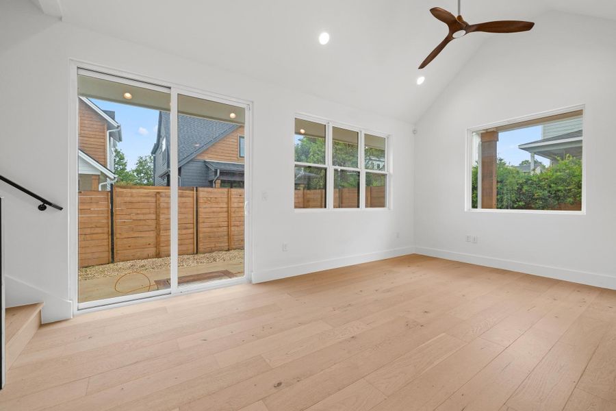Unfurnished room featuring healthy amount of natural light, recessed lighting, ceiling fan, hardwood / wood-style floors, and high vaulted ceiling Unfurnished room featuring healthy amount of natural light, recessed lighting, ceiling fan, hardwood / wood-style floors, and high vaulted ceiling