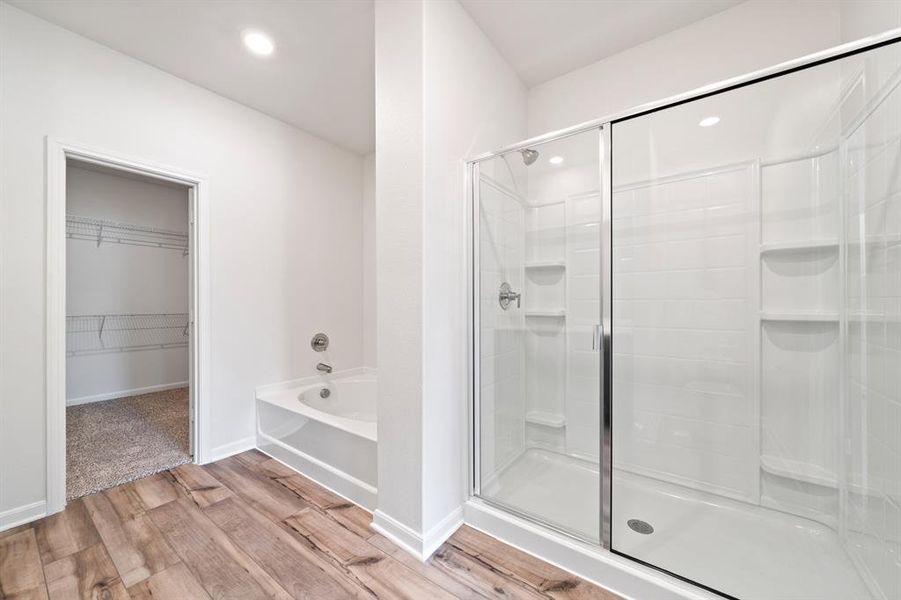 Bathroom with hardwood / wood-style flooring and shower with separate bathtub