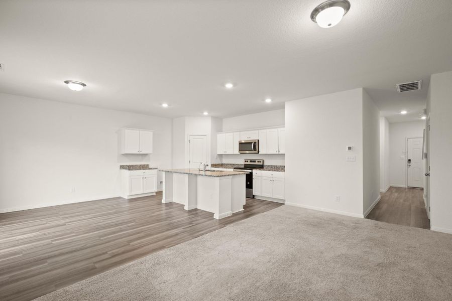 Kitchen with white cabinets, appliances with stainless steel finishes, open floor plan, an island with sink, and recessed lighting