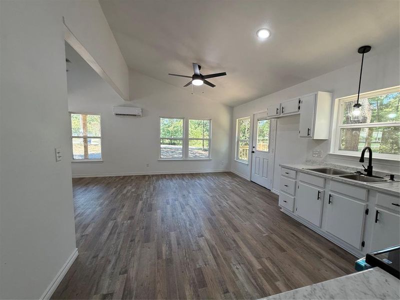 Kitchen featuring white cabinets, vaulted ceiling, light countertops, healthy amount of natural light, and recessed lighting